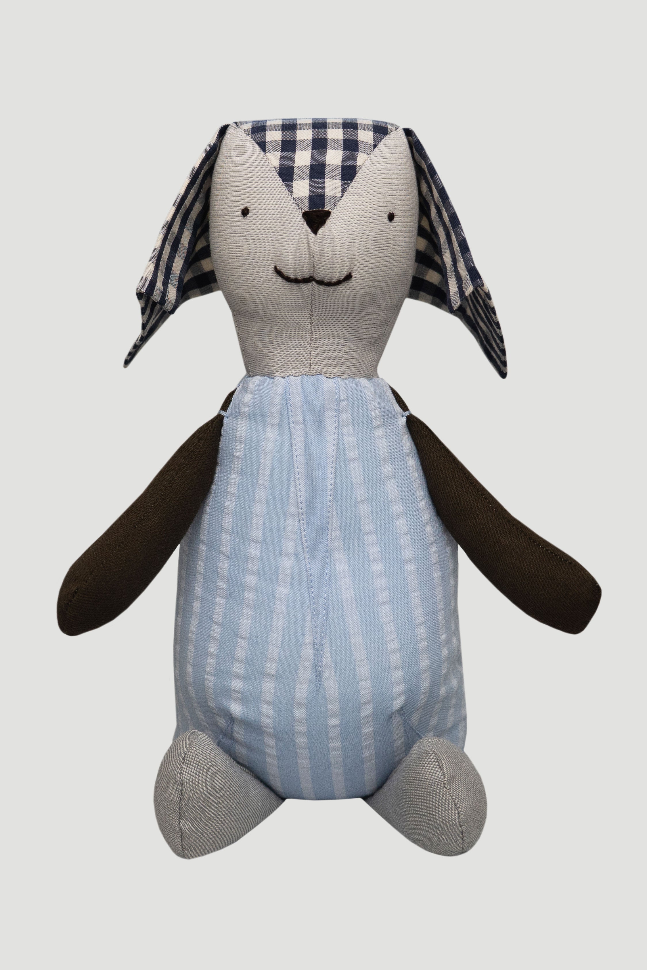 Teddy toy with checkered ears, striped blue body, brown arms and grey legs 