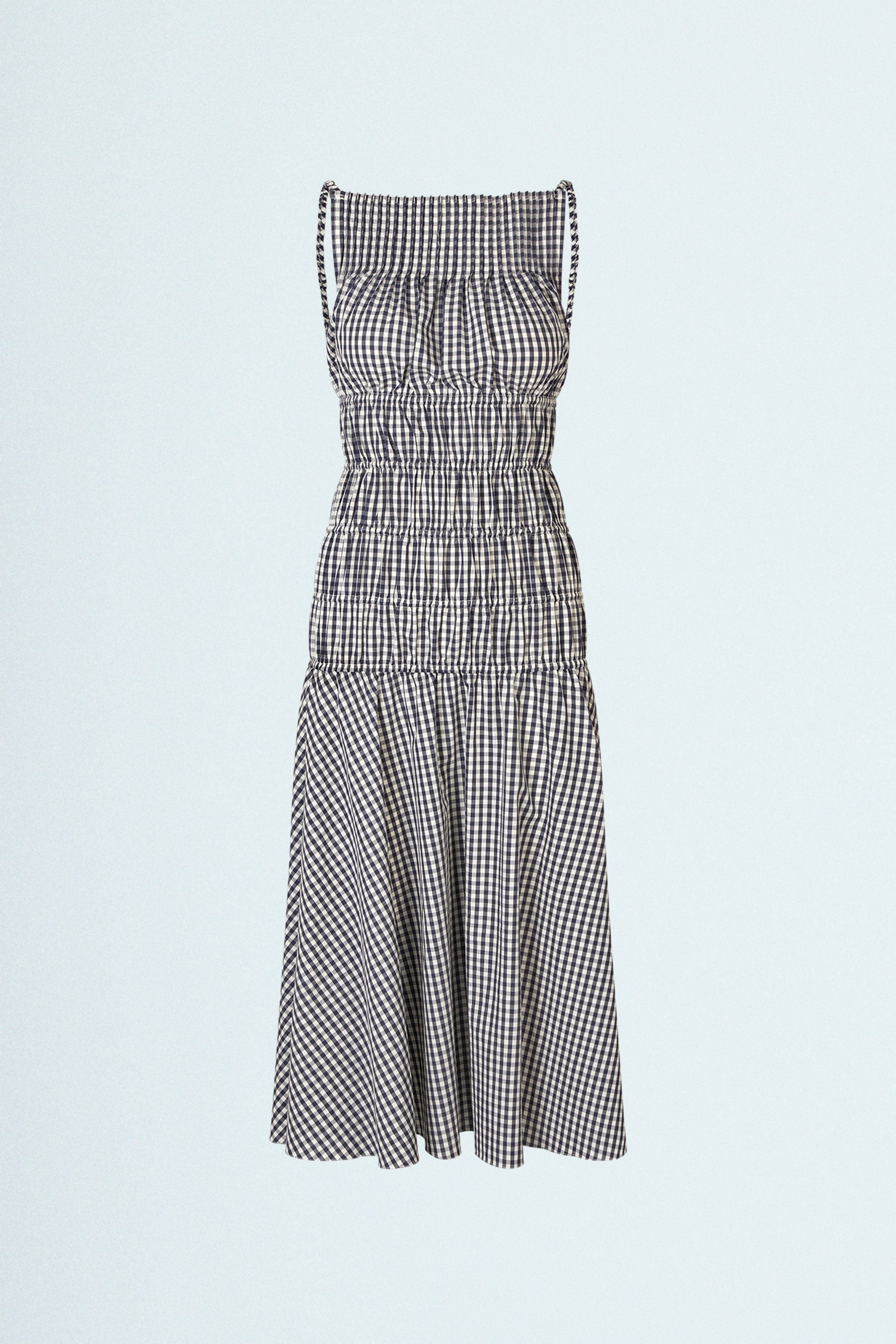 LINÉ Pintuck Dress Navy. Pintucks at neckline · Elastic shoulder straps · Elastic casings around body · Open back adorned by tie bands to secure front · Flared midi skirt · The flexible construction of the body ensures a comfortable fit and can even be used during pregnancy · Model is 162 cm and wears size 1 · Made-to-order · Produced locally in Denmark · Material: 100 % organic cotton yarn dyed gingham · Collection: Gingham Garments. LINÉ