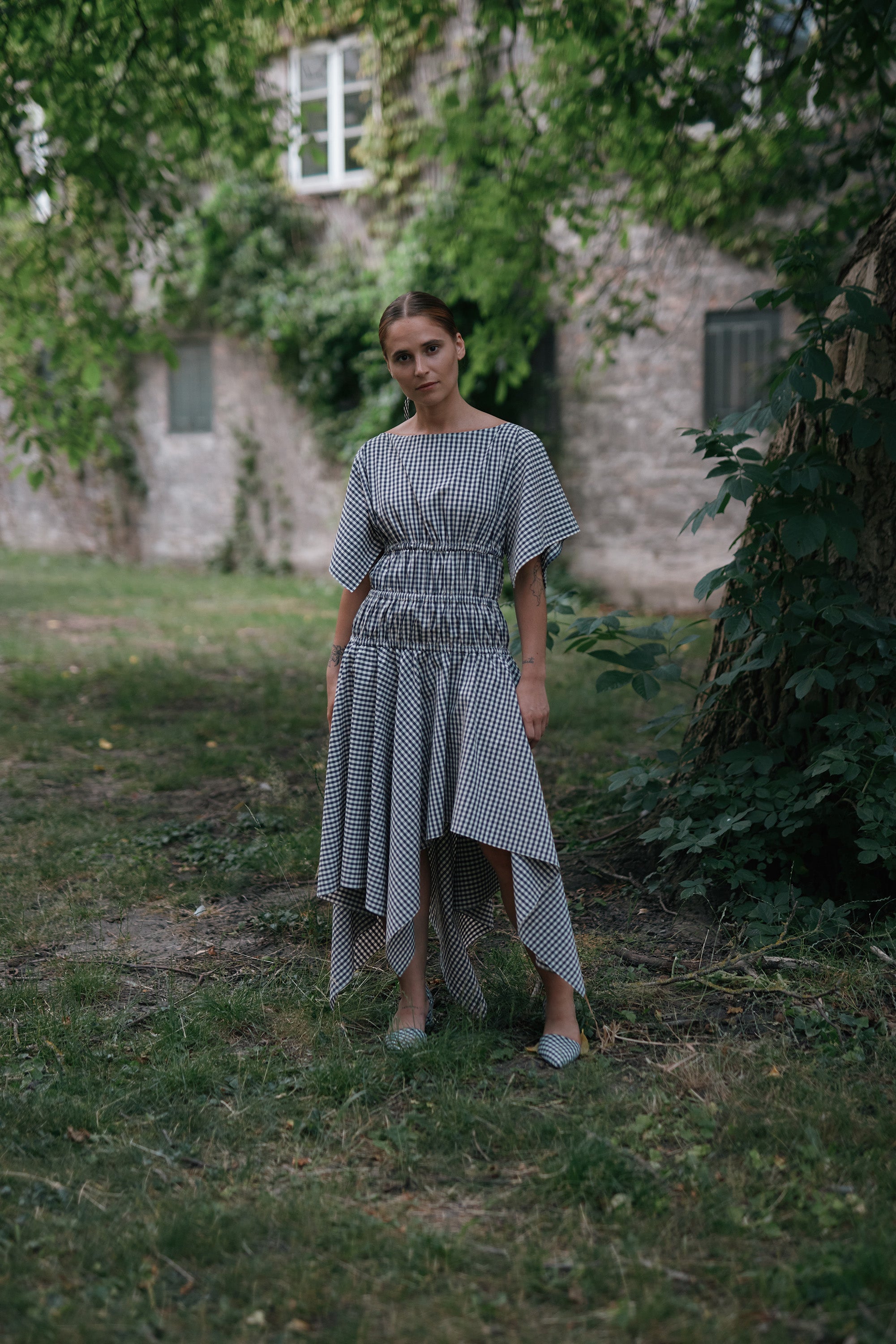 Square Dress Navy. Boat neck · Elastic casing under the bust, around waist and hips · Flared mid length sleeves · The asymmetric skirt is slightly longer in the back · Model is 162 cm and wears size 1 · Made-to-order · Produced locally in Denmark · Material: 100 % organic cotton, yarn dyed gingham · Collection: Gingham Garments. LINÉ