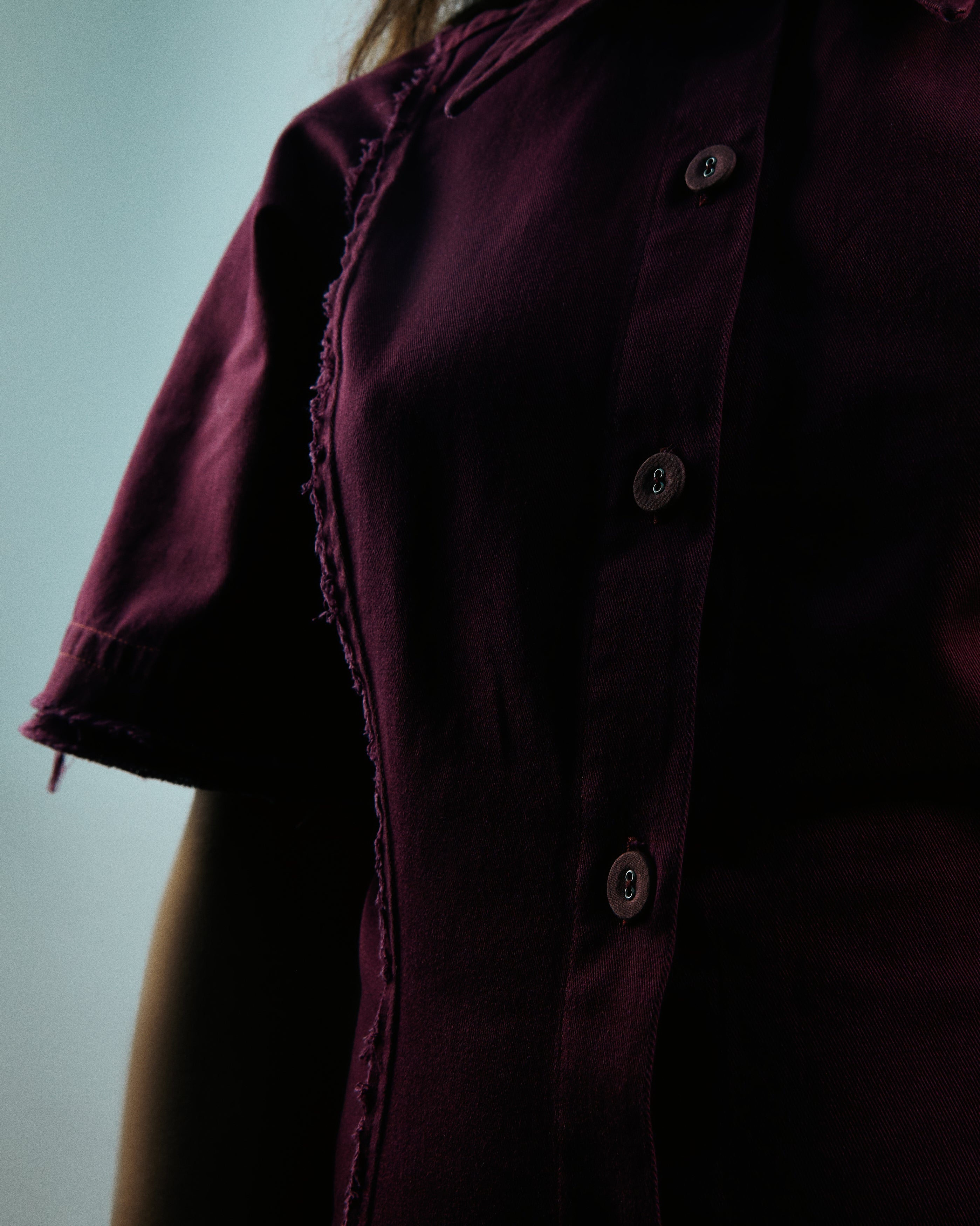 Close-up of a dark purple shirt with buttons on a blurred background
