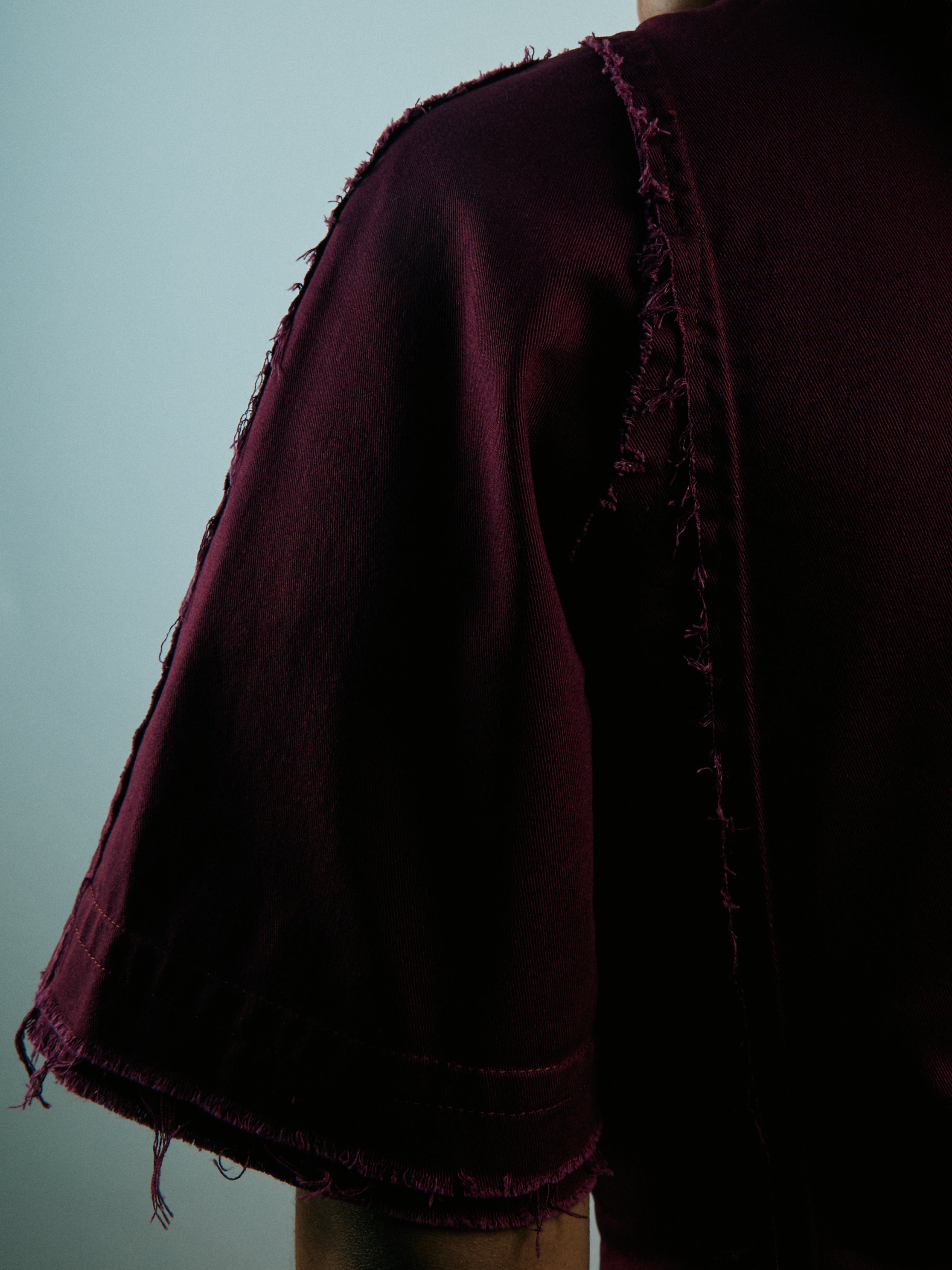 Dark purple garment with frayed edges on a plain background