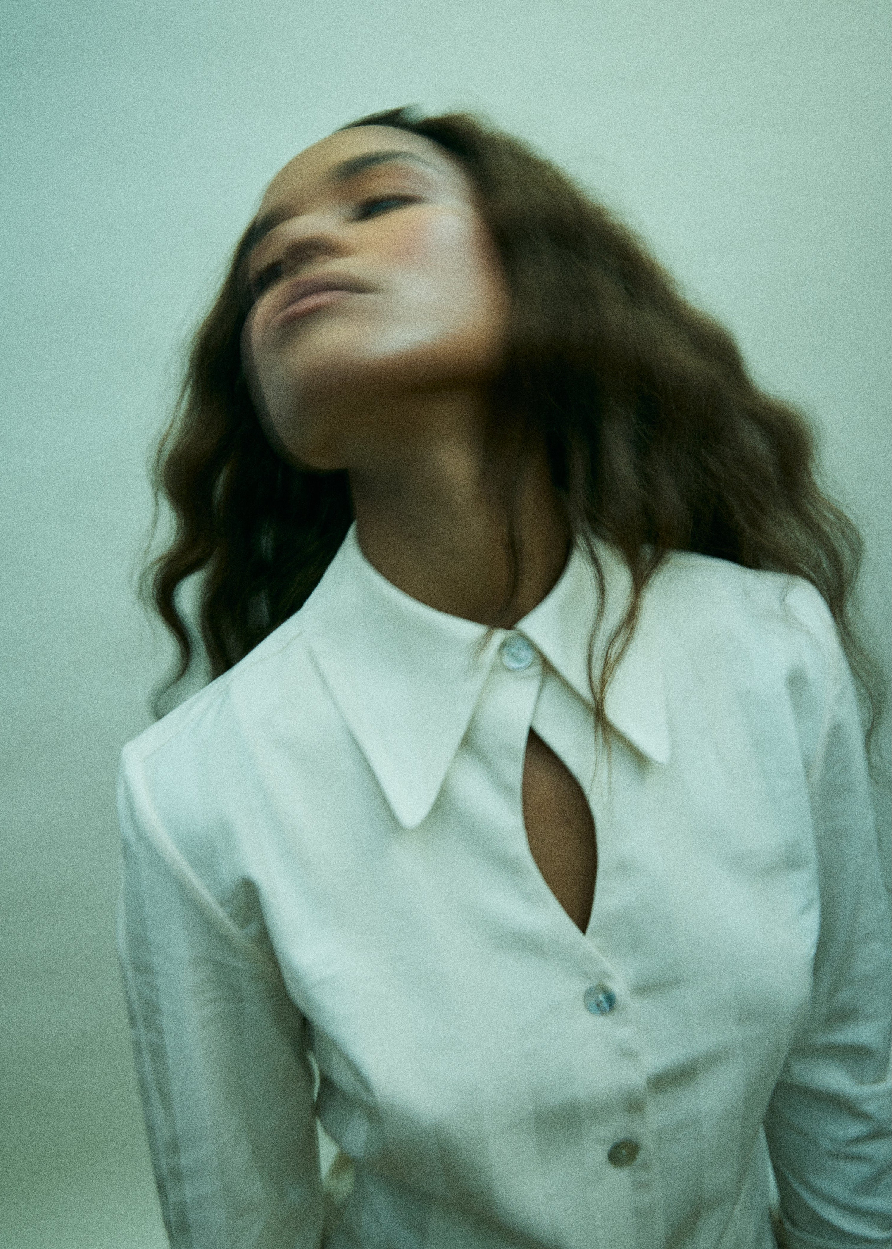Woman wearing a white blouse with a cut-out design on a plain background
