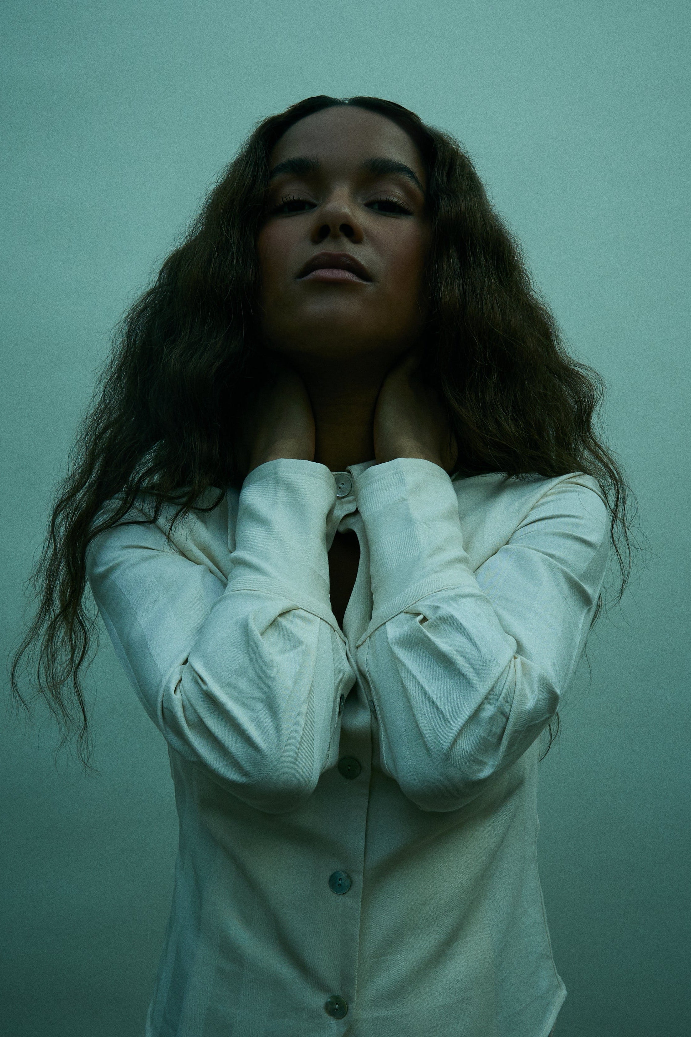 Woman wearing a white shirt against a greenish background