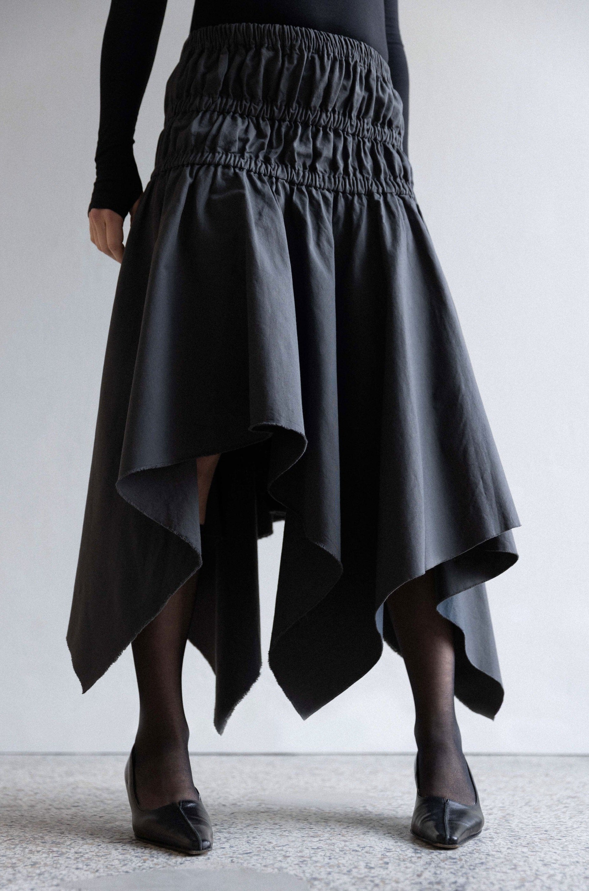 LINÉ, Twill Tweaks,  Asymmetric Square Skirt, Anthracite  - Knee / midi asymmetrical skirt - Elastic waistband - Elastic casings around hips - Raw edge on hem  Model is 168cm and wears size 1 Made-to-order Produced locally in Denmark Material: 100% GOTS certified organic cotton twill