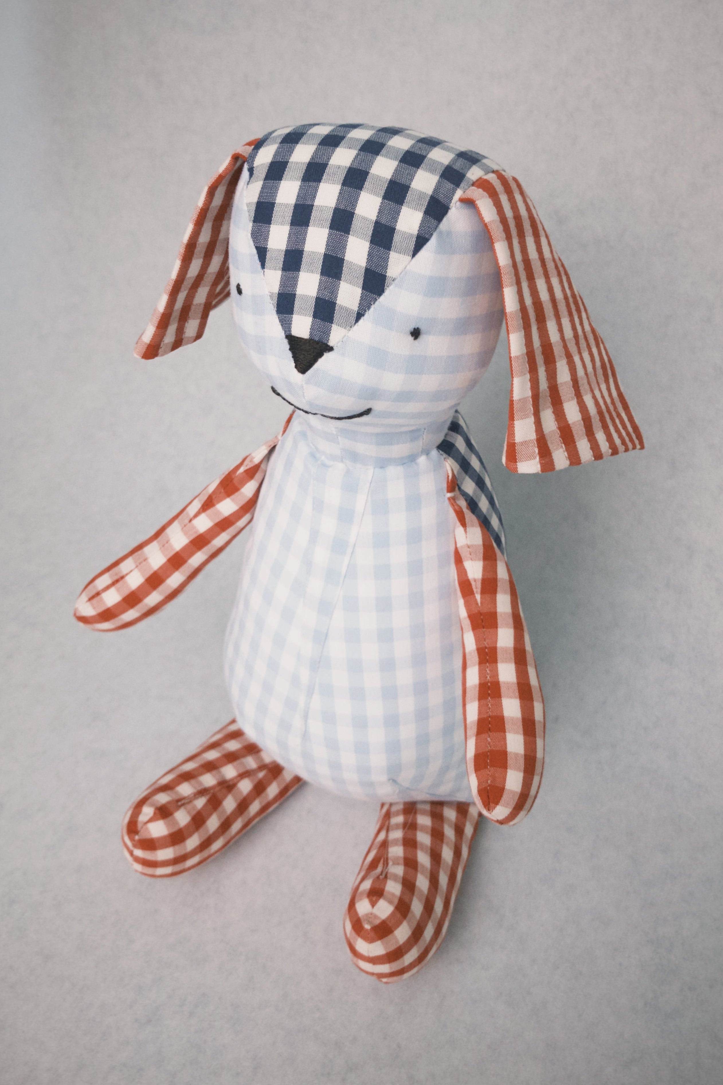 Stuffed teddy toy with checkered pattern on a gray background